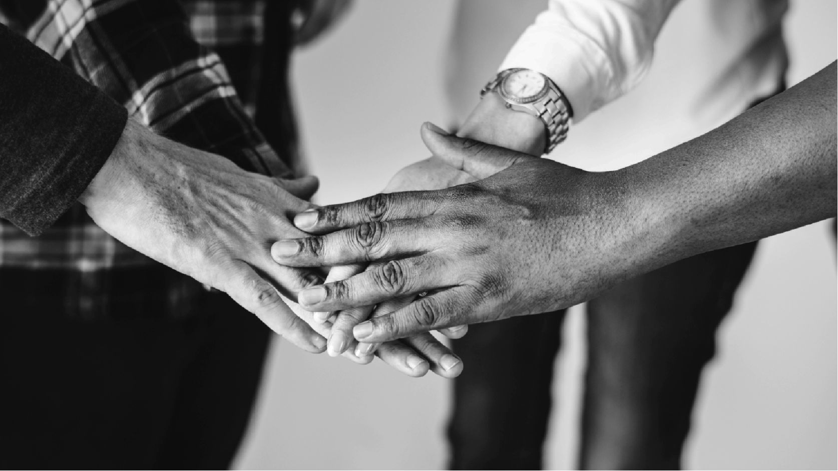 A team of diverse employees stack hands, symbolizing unity and inclusivity