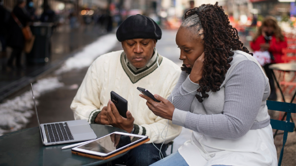 Two South African individuals focused on smartphones, illustrating modern urban tech usage